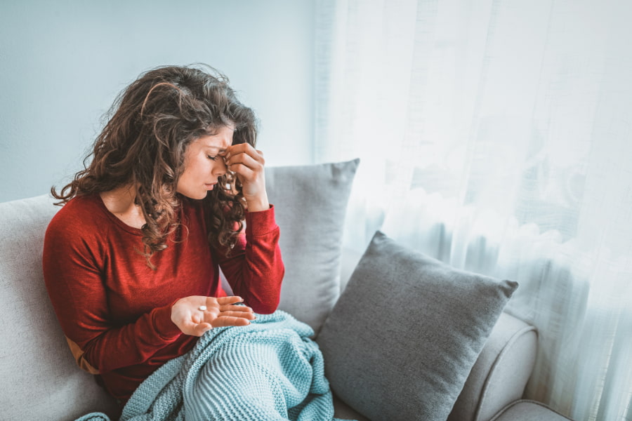 woman sitting on a couch and experiencing a headache