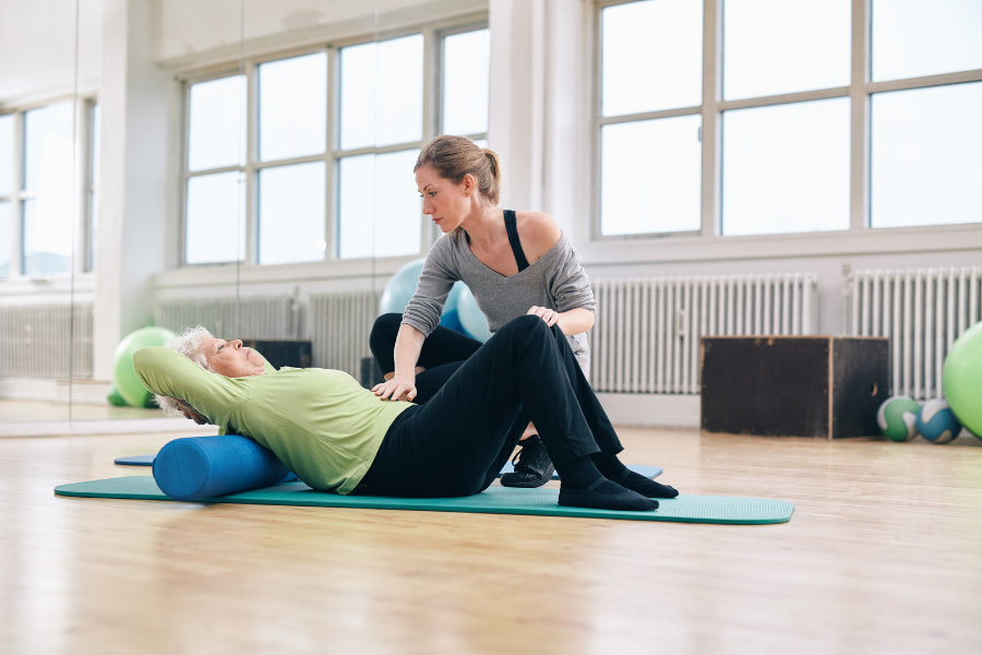 image of a senior woman stretching her back with a personal trainer